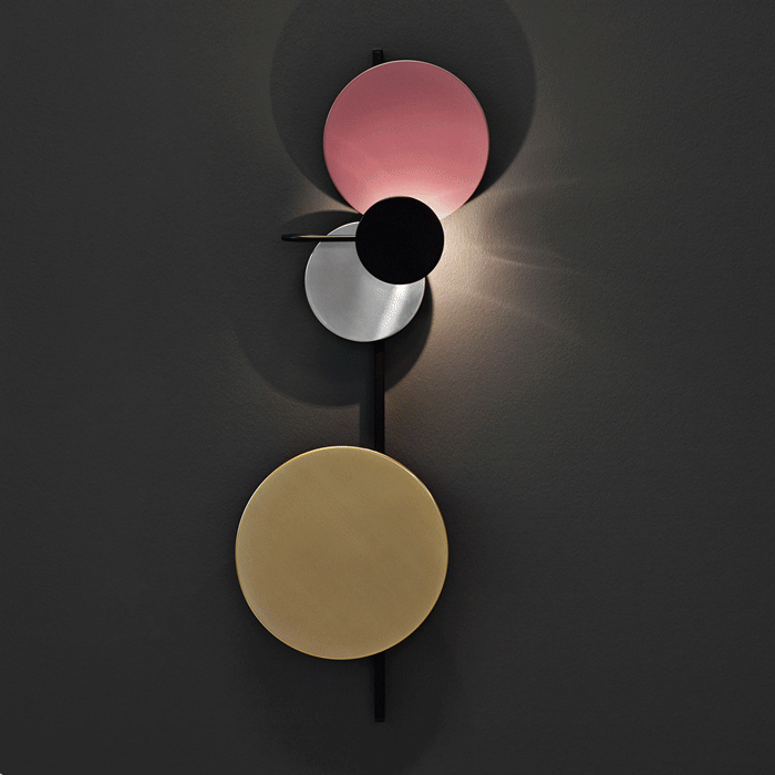 Pink-toned disc fixture illuminated on a dark wall