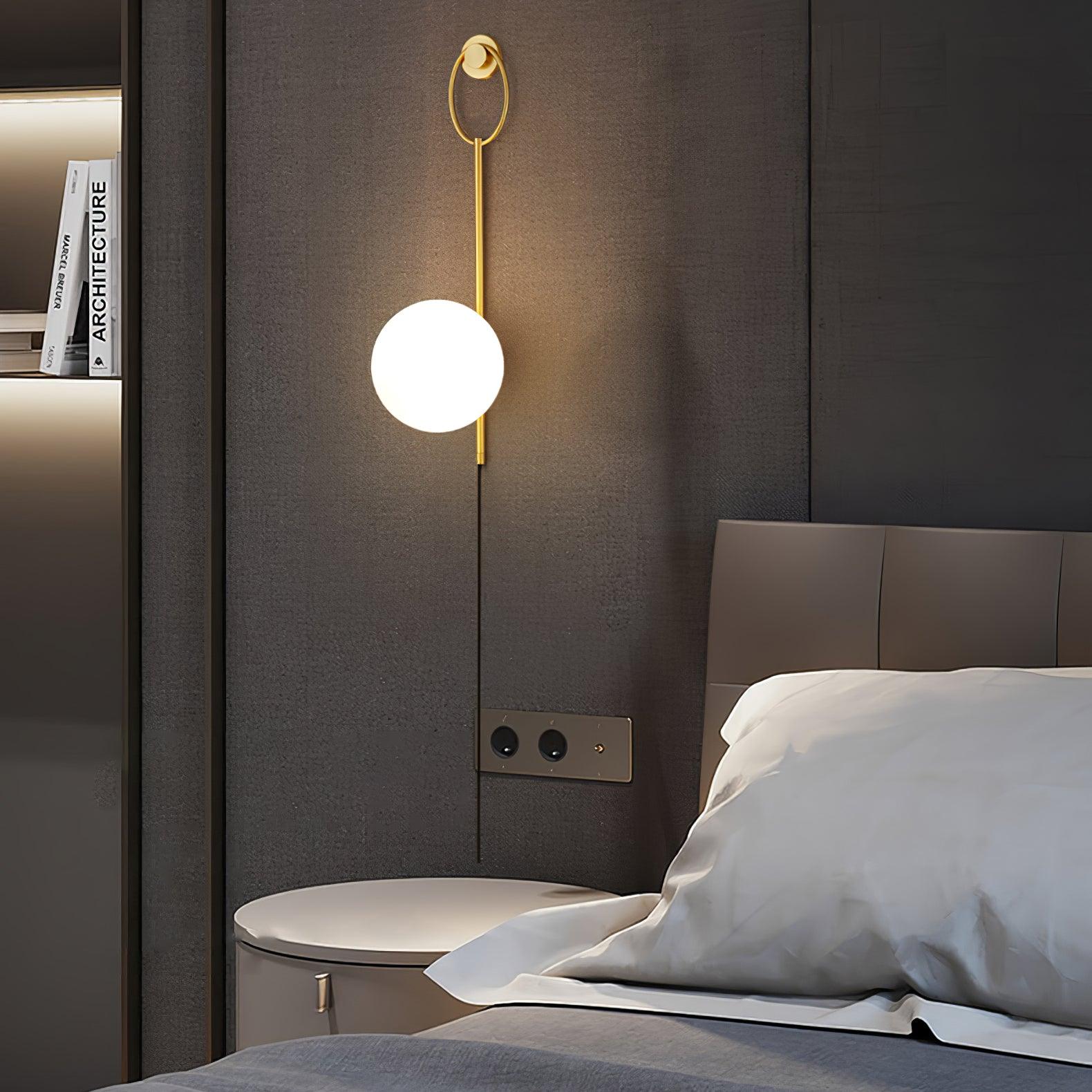 Slim globe wall lamp above a bedside table