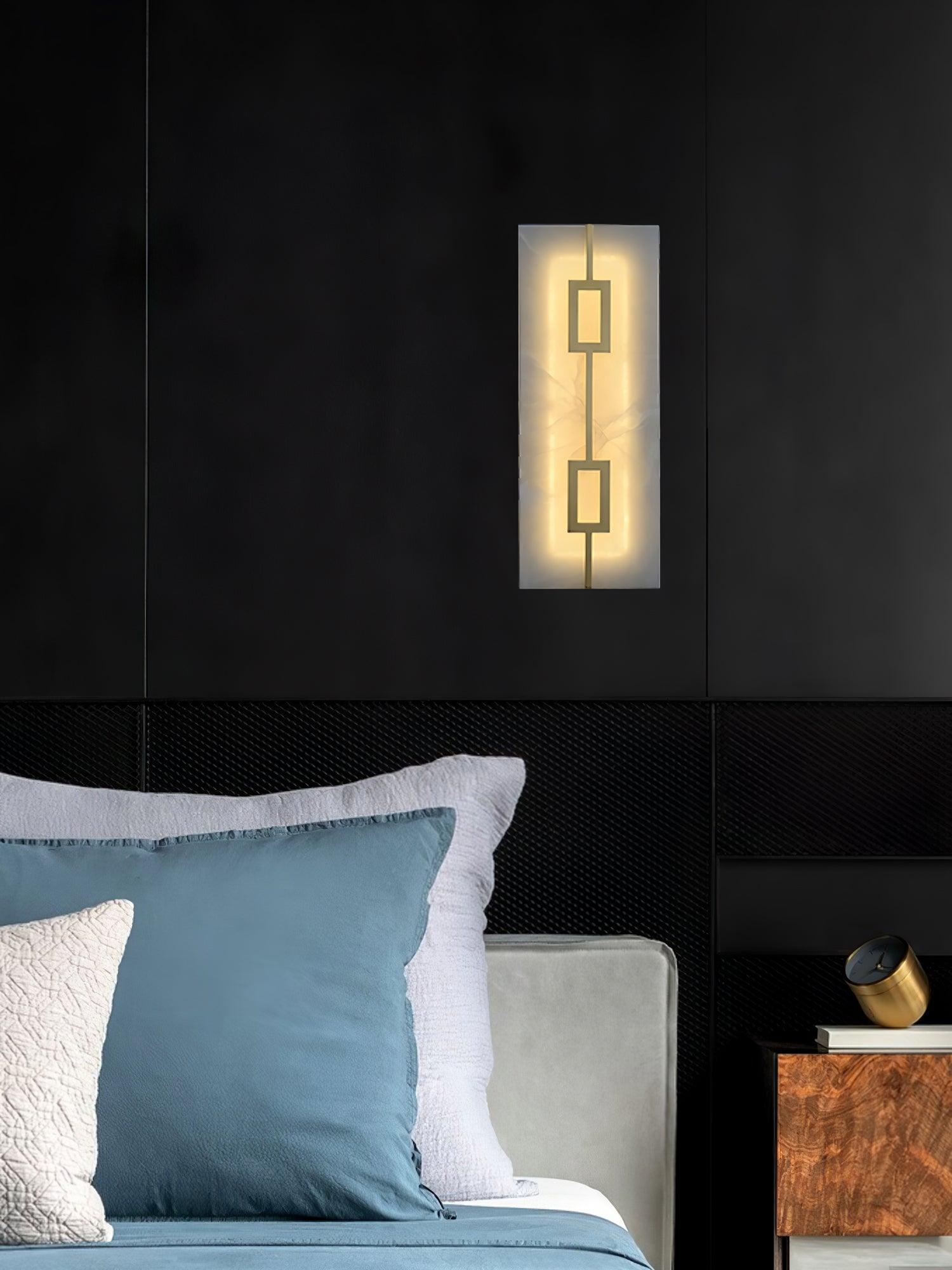 Portrait bedroom view of rectangular stone-look wall light beside blue pillows and a wood-pattern bedside cabinet