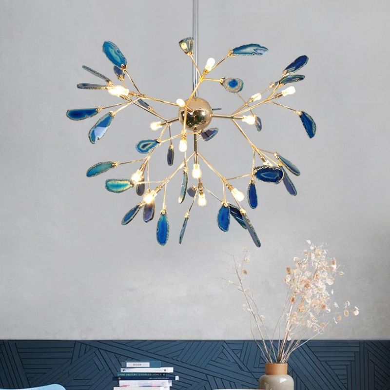 Large blue branching stone-leaf pendant above books and a vase against grey and dark blue patterned walls