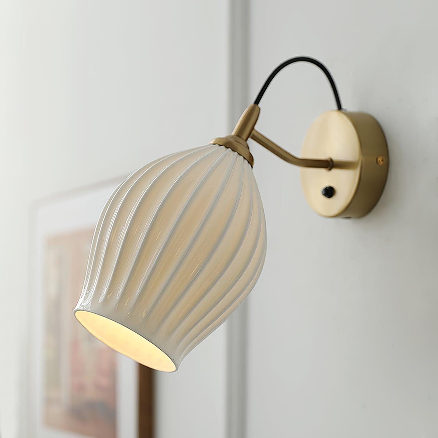Lit ribbed ceramic shade beside a round metal plate