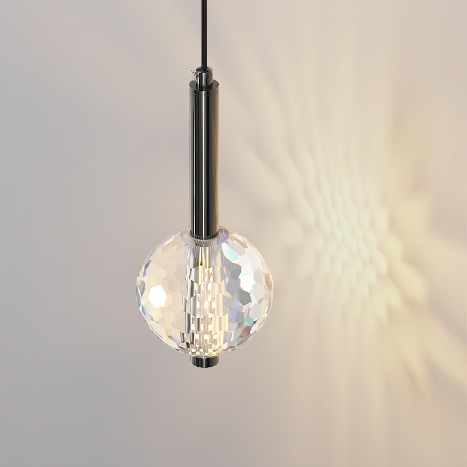 Close-up of lit faceted globe, cylindrical dark neck and suspension entry, with warm-looking pattern on the wall