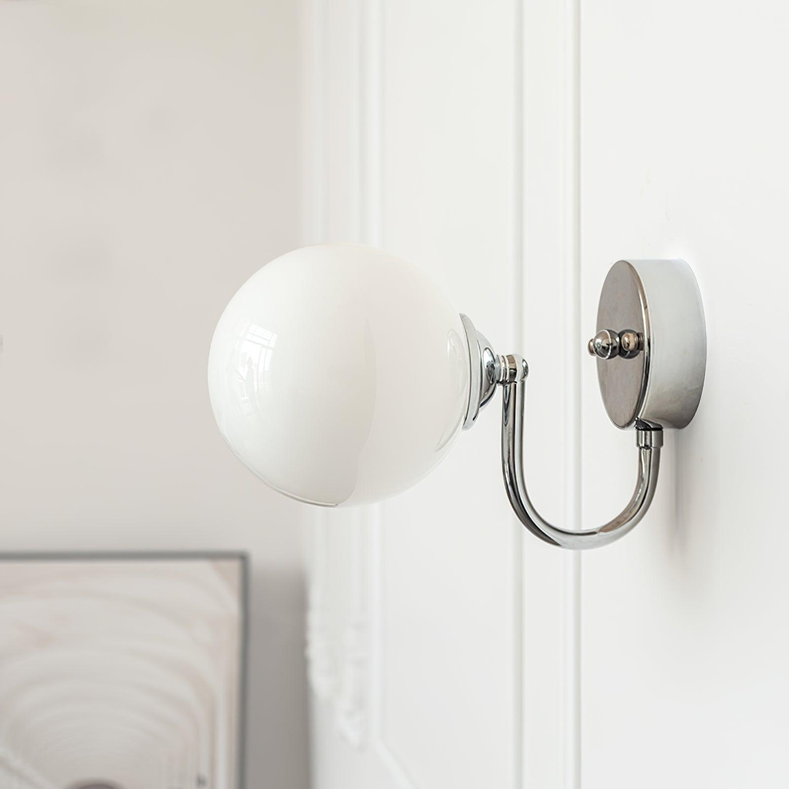 Unlit globe at left of a round plate and lower curved arm on a white panelled wall, with a framed print partly visible