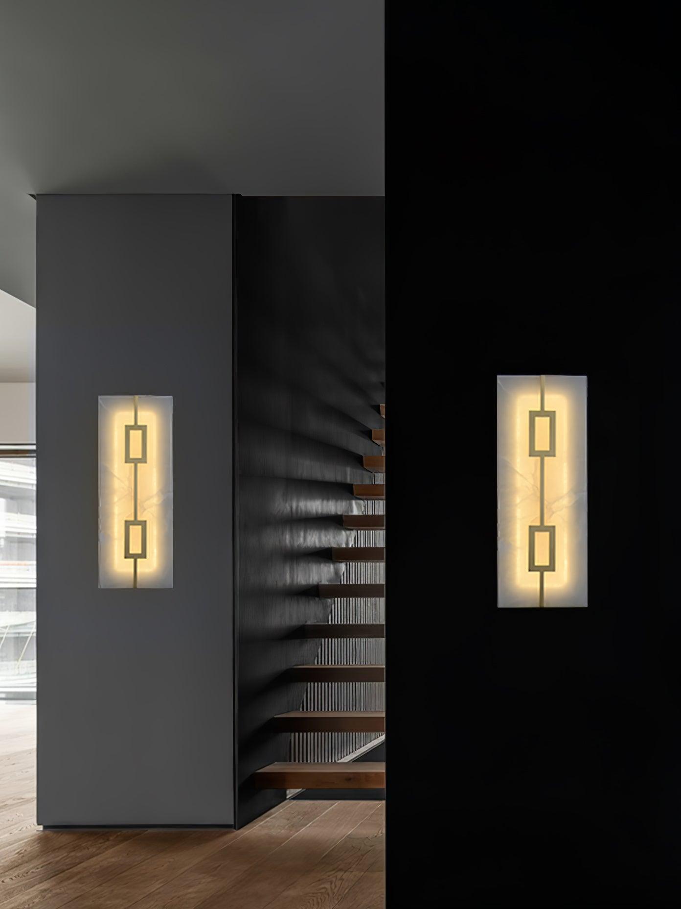 Two tall geometric wall lights on separate dark and grey walls beside an open staircase