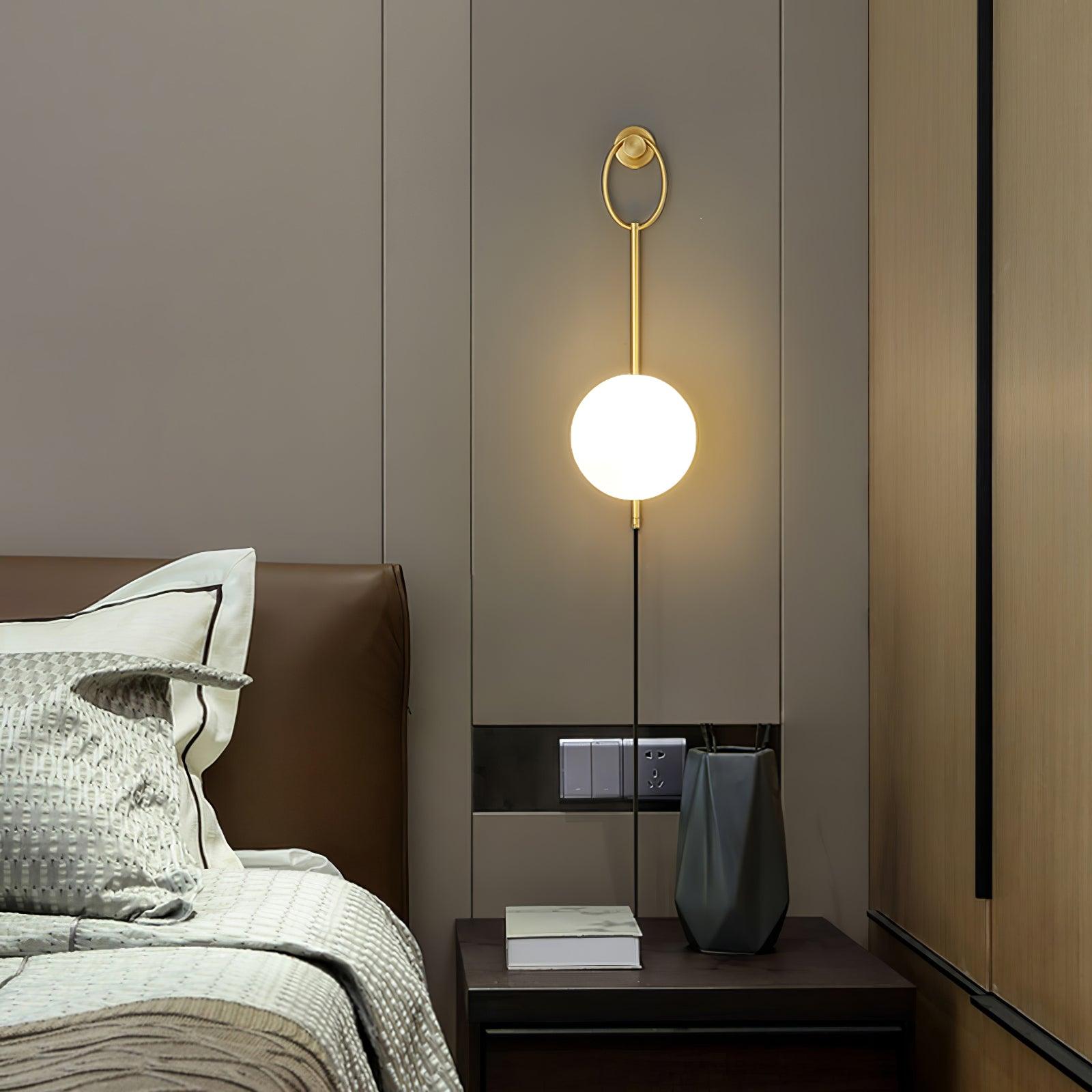 Gold-toned ring and White globe beside a bed