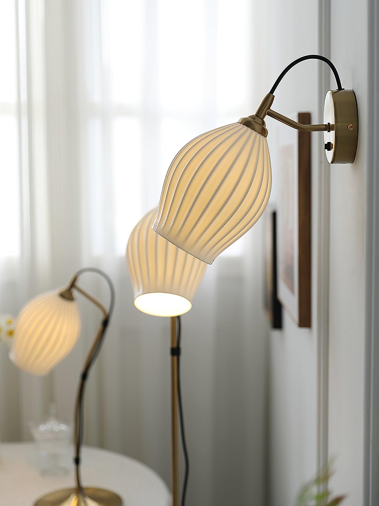 Lit ceramic wall fixture near other ribbed lamps