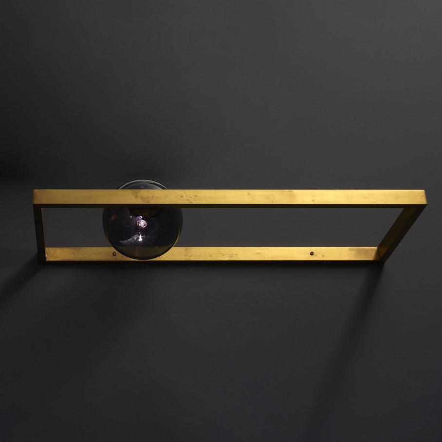 Gold-toned frame with dark globe against a dark wall
