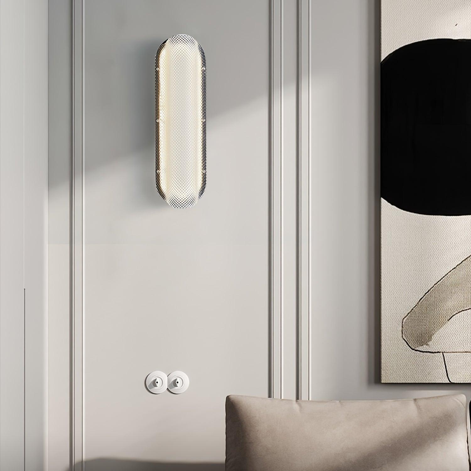 Lit Vale wall light on a moulded wall beside artwork, above two round wall controls and a cushion