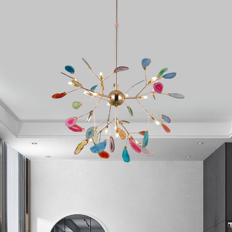 Multicolour stone-leaf pendant with gold-tone branching arms above a grey wall and arched mirror