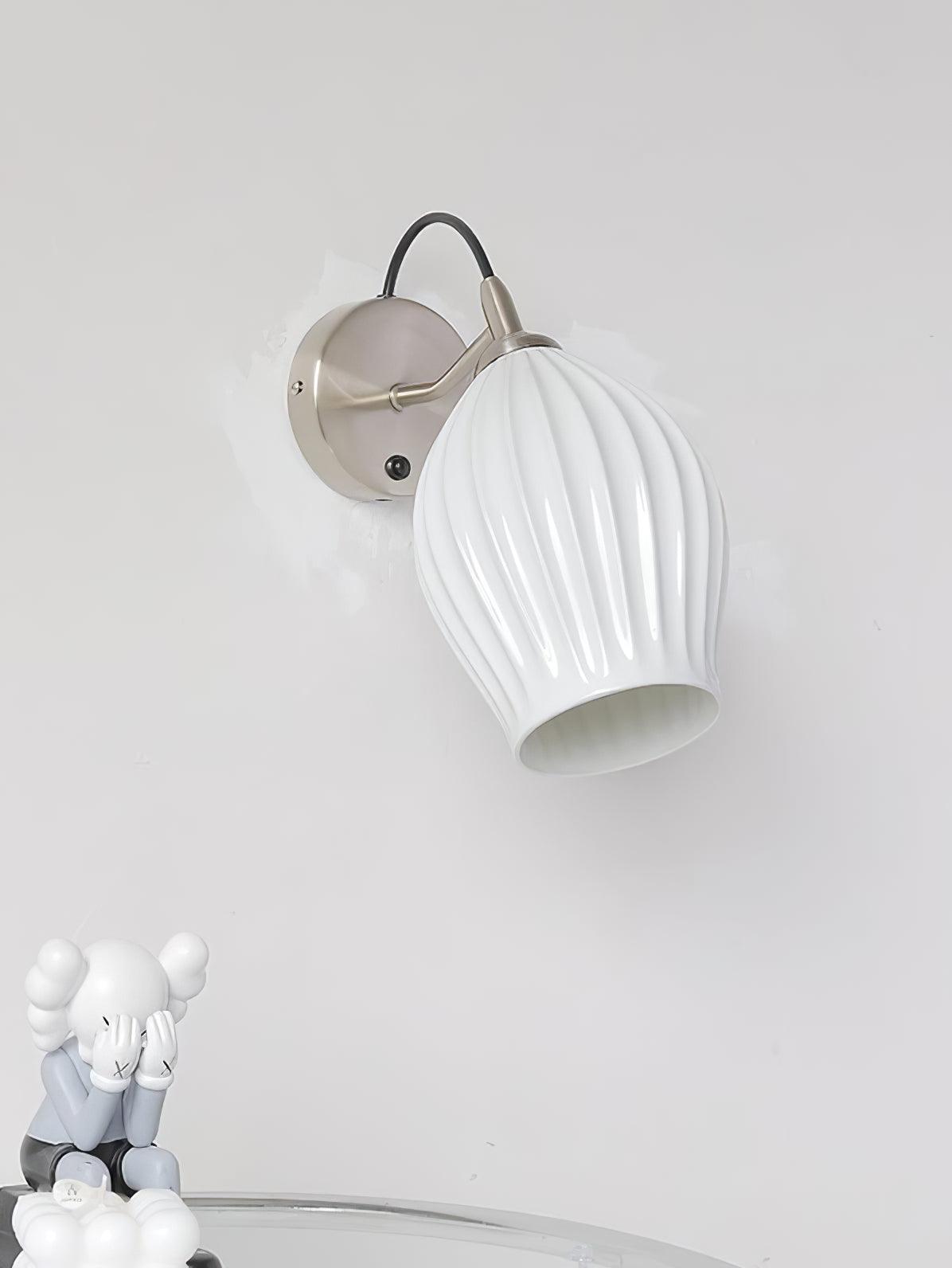 Unlit white ribbed wall shade above a small decorative figure
