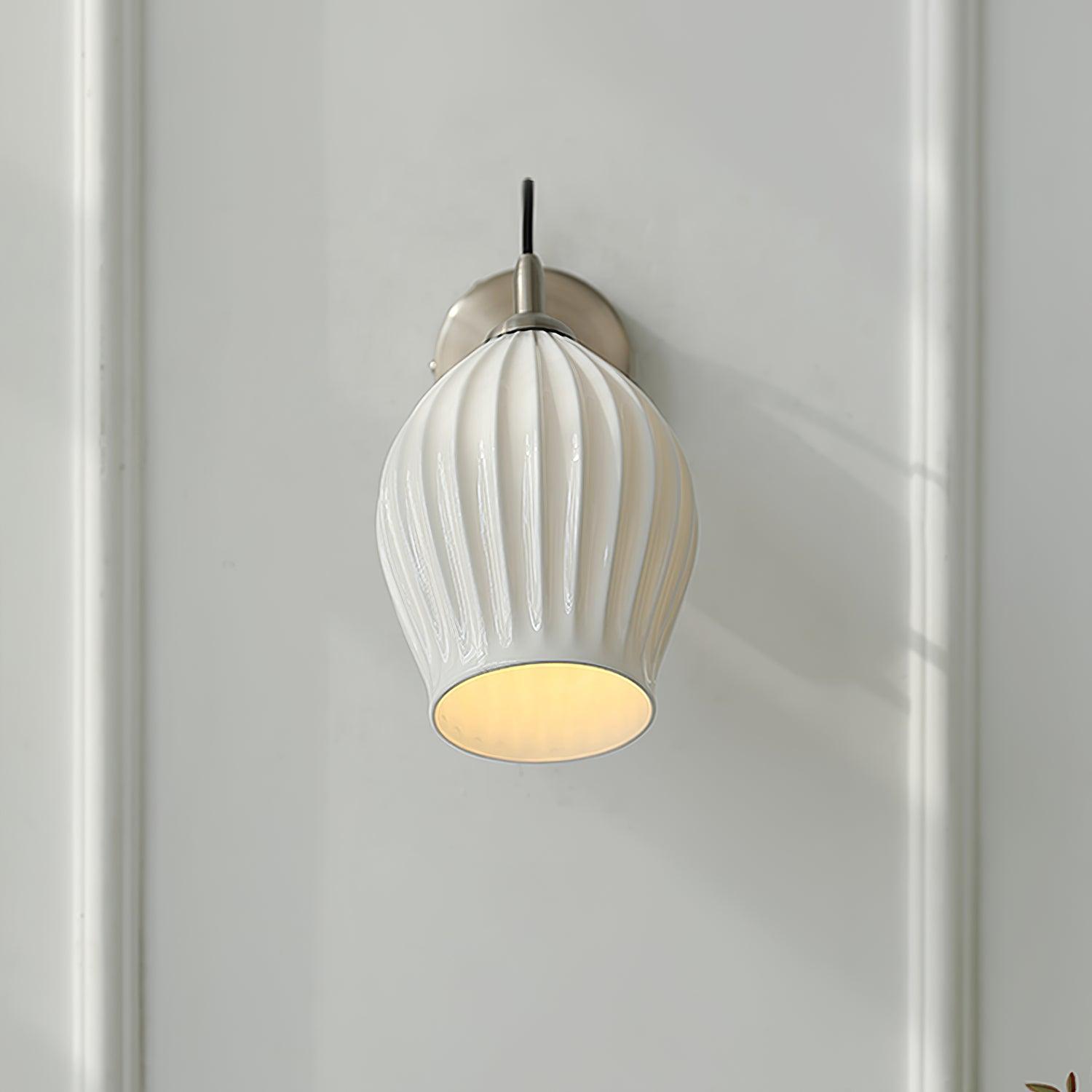 Front view of a lit ribbed ceramic wall shade