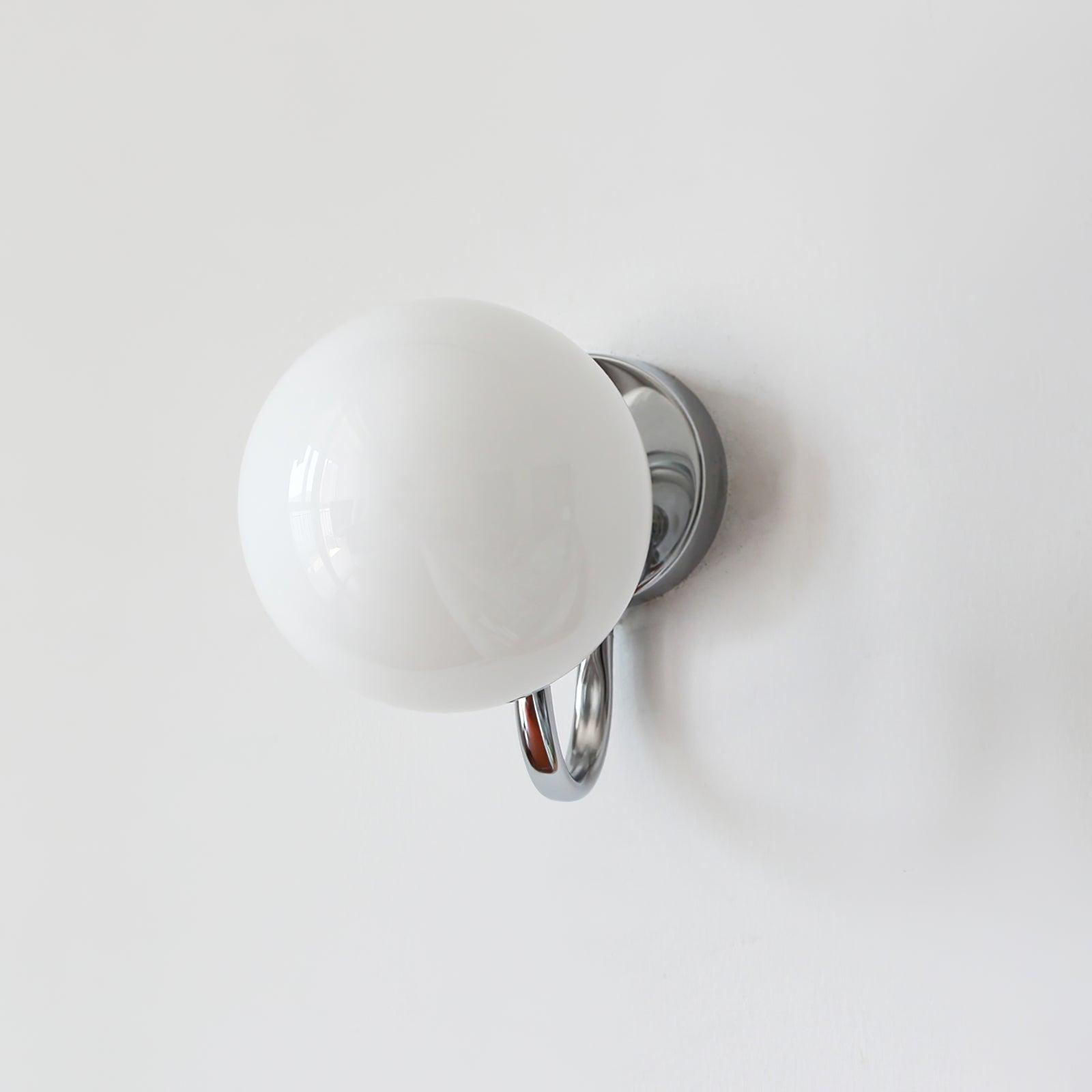 Near-front white globe partly covering the round wall plate behind it, with chrome-coloured U-shaped arm below