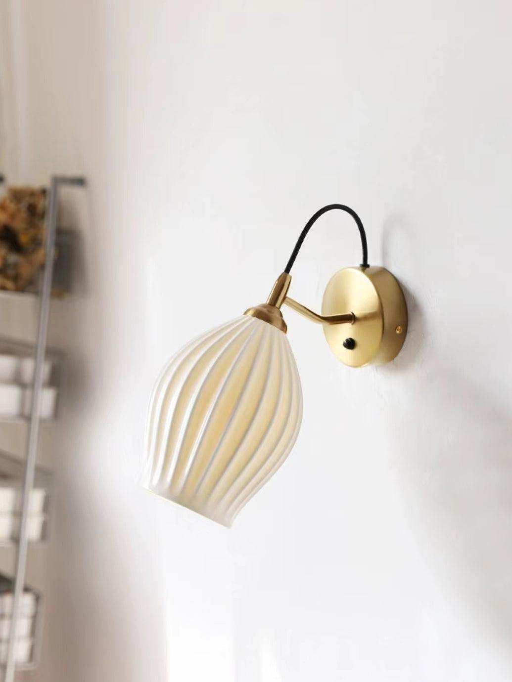 Gold-coloured wall fitting with a glowing ceramic shade
