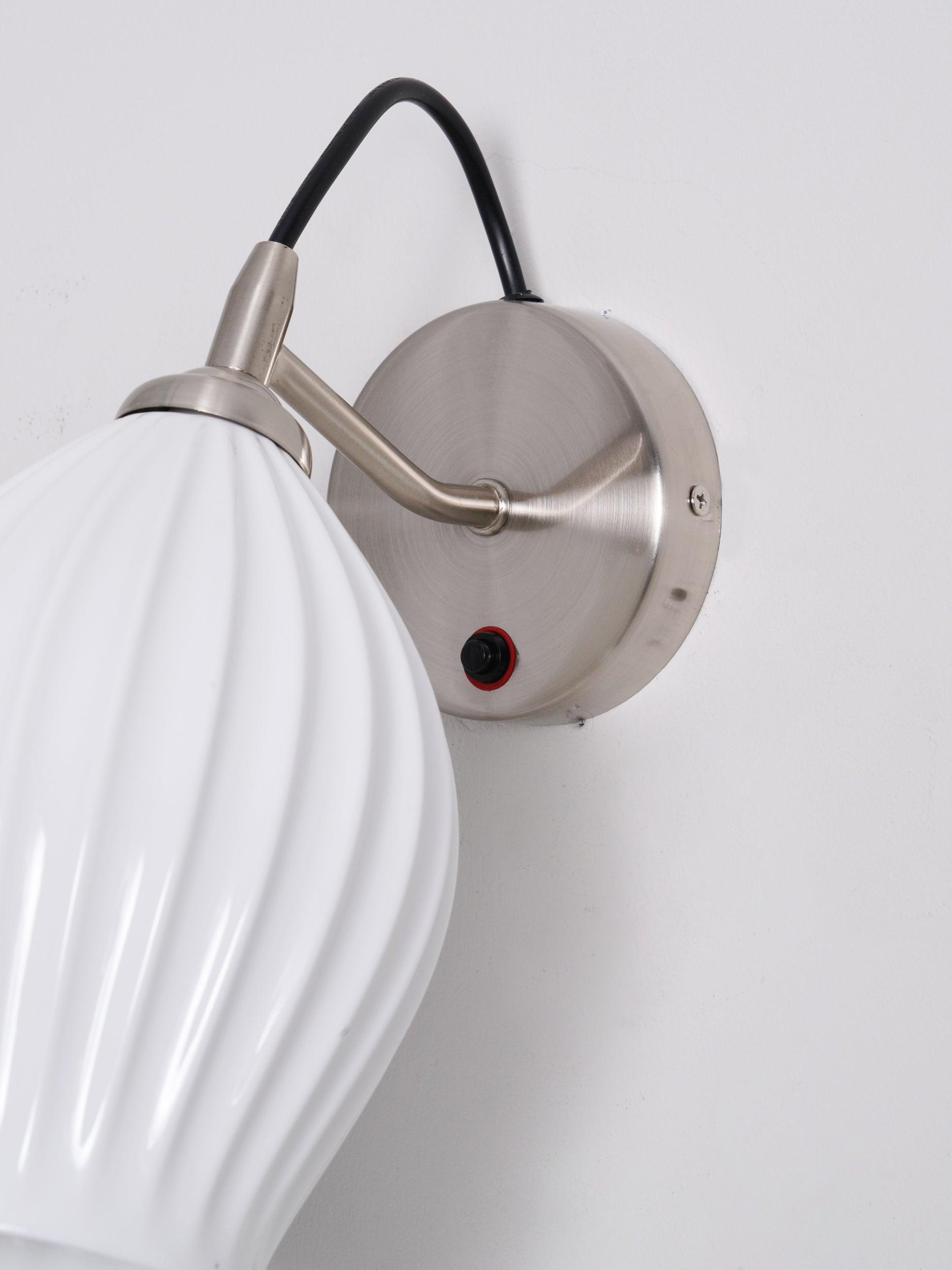 Close-up of white shade, metal arm and round backplate