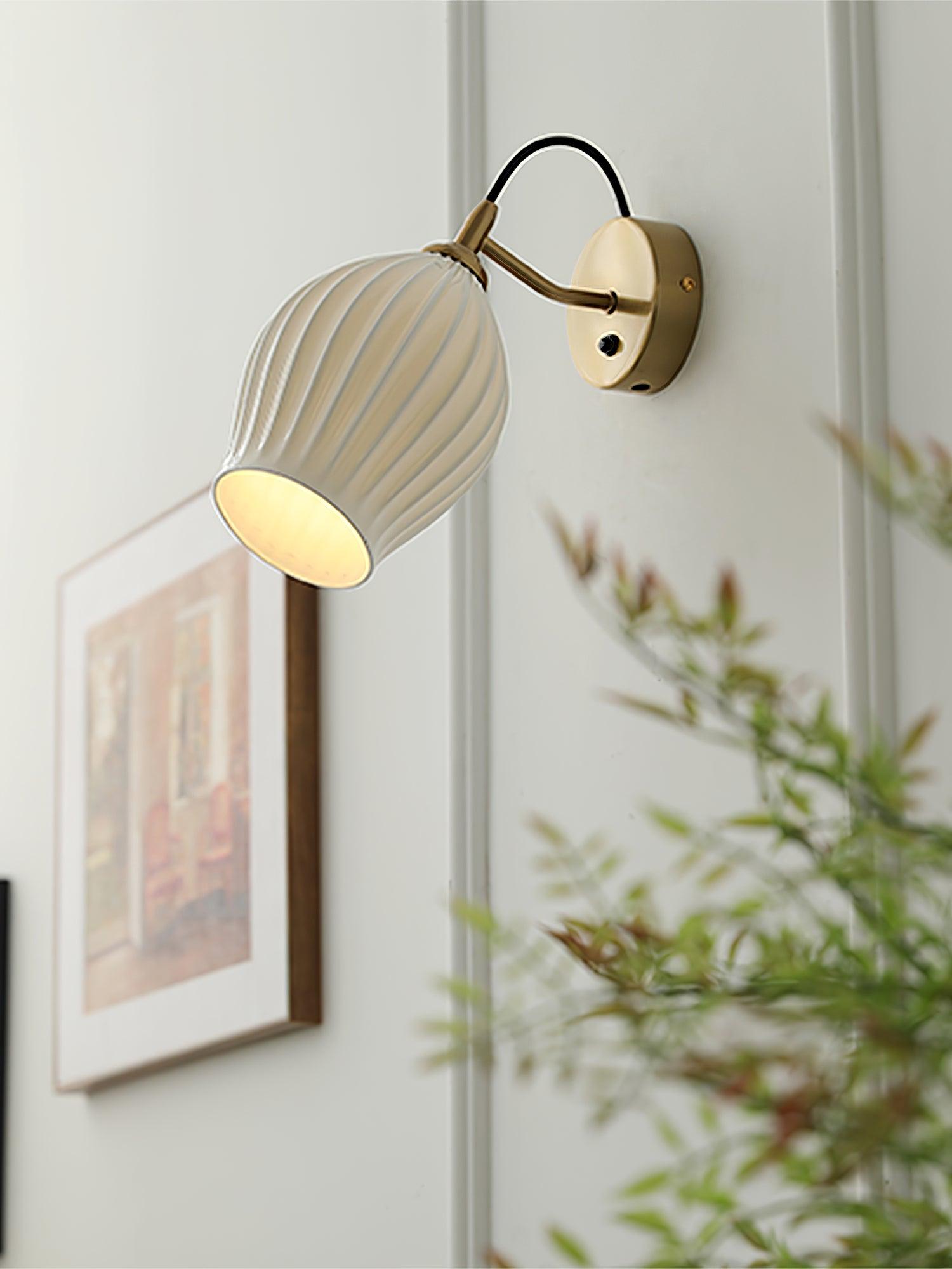 Ceramic wall light above framed artwork and greenery