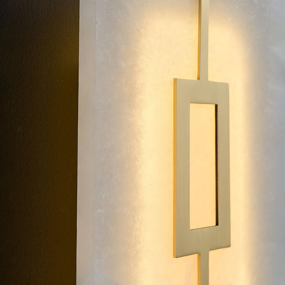 Angled close-up of brushed brass-tone open rectangular motif against glowing pale veined panel