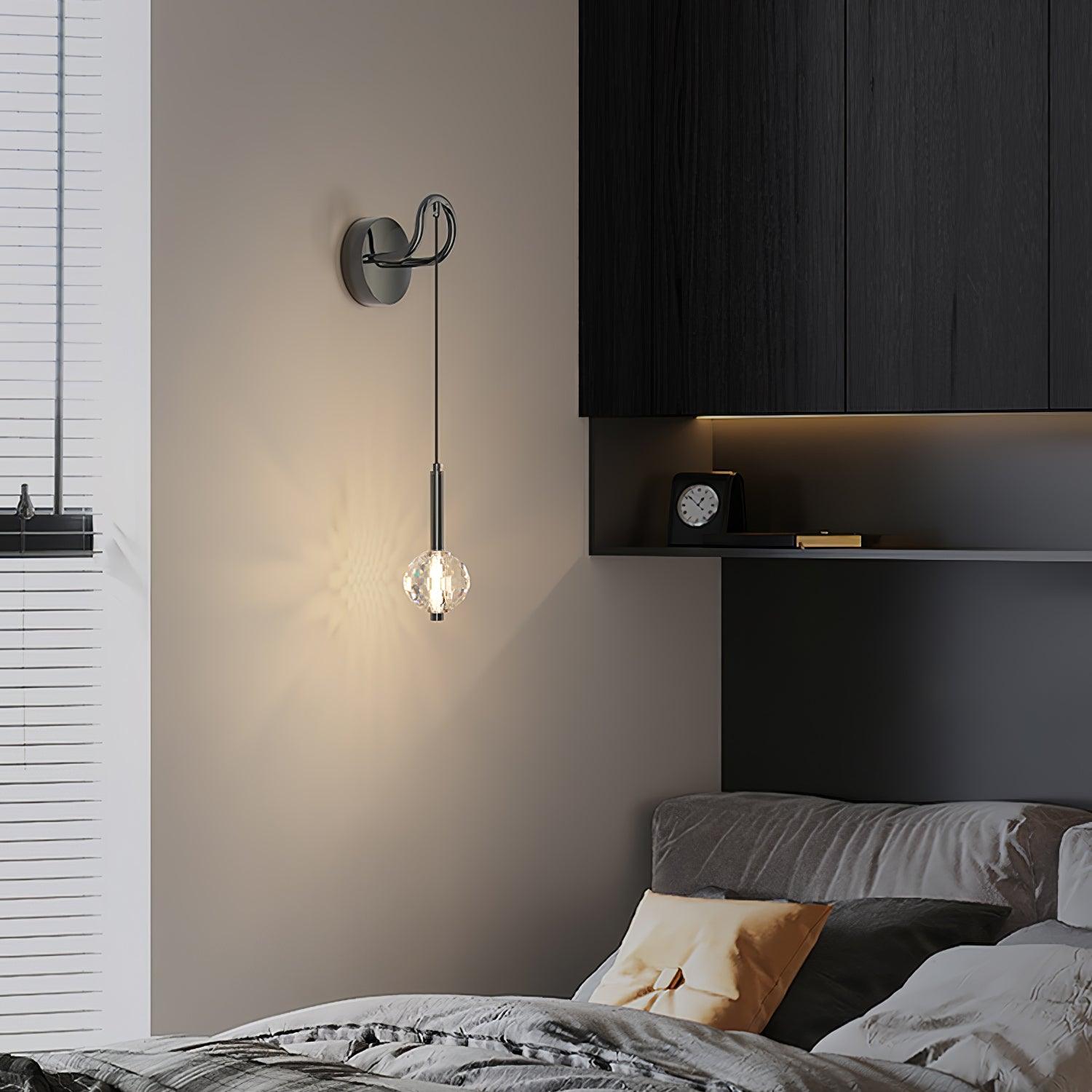 Lit faceted glass globe beside a grey bed, window blinds and dark cabinets, with patterned light on the wall