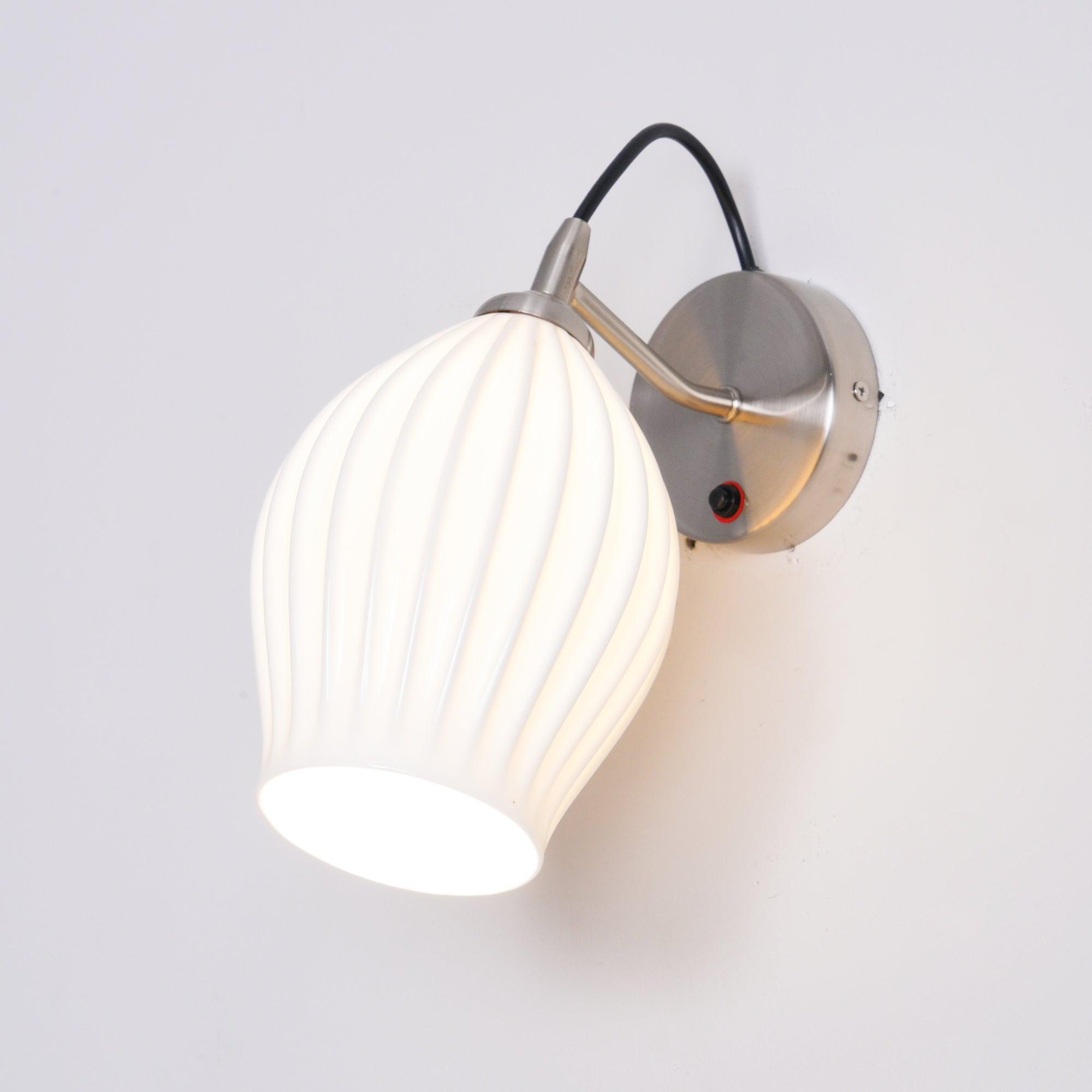 Lit ceramic shade and curved arm on a round wall plate