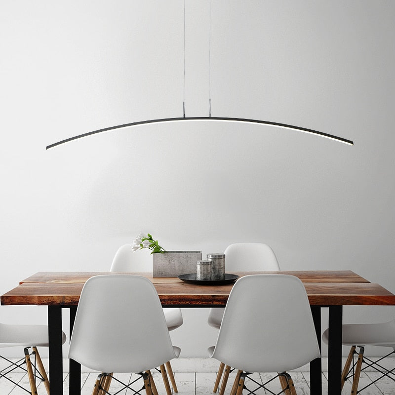 Black Edge arched pendant above a wooden dining table and white chairs.