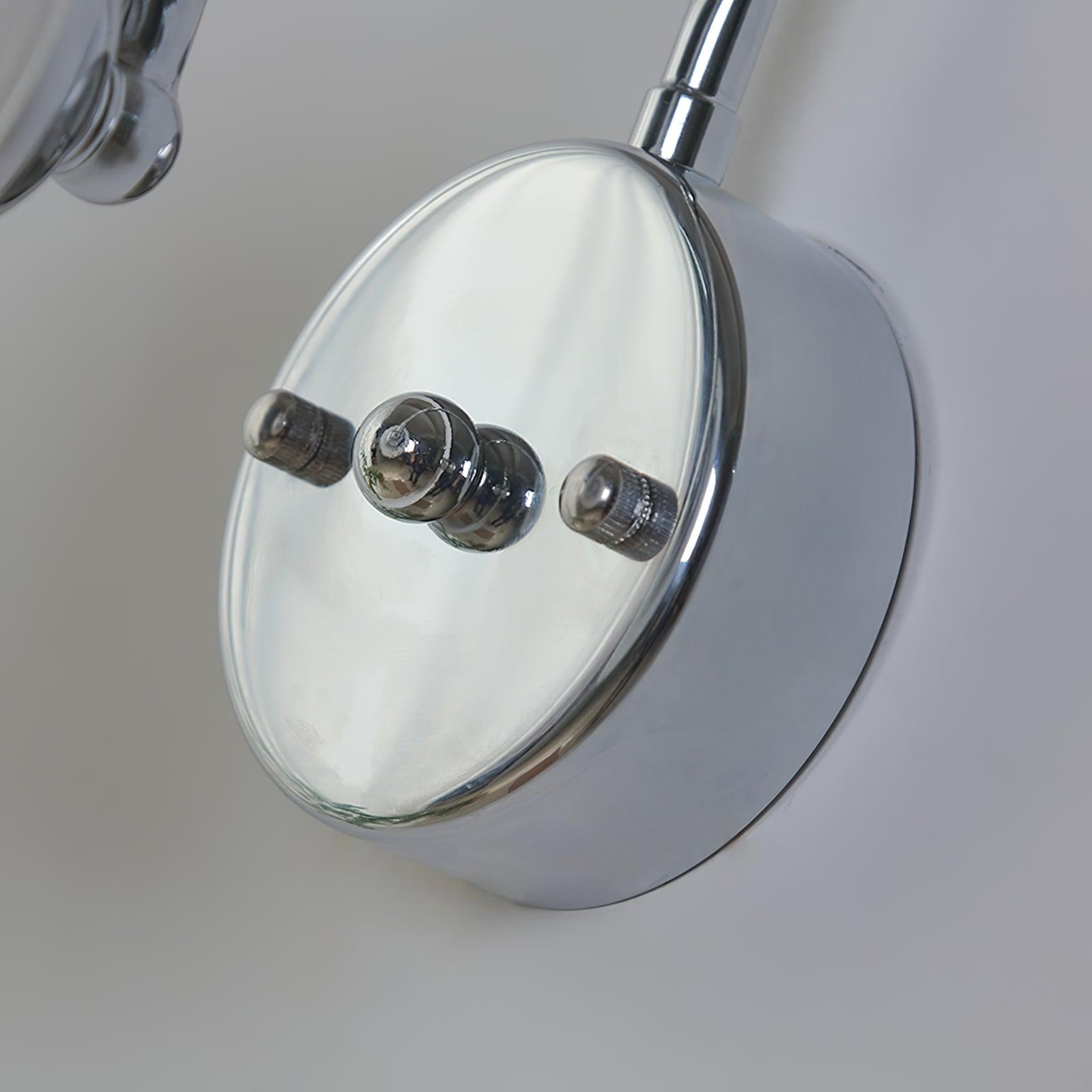 Close-up of reflective round wall plate with raised central projection, two textured caps and arm above