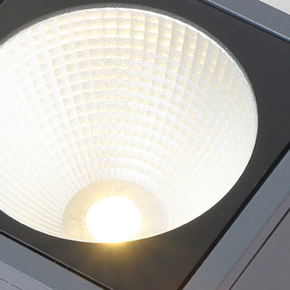 Orr lit round faceted reflector inside a black square frame, with a pale yellow centre and warm-looking glow.