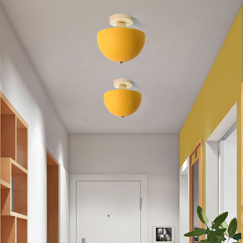 Yellow Ozawa Bowl ceiling lights in hallway with yellow wall, mirror and green plant, wood cubby shelves and white entry door