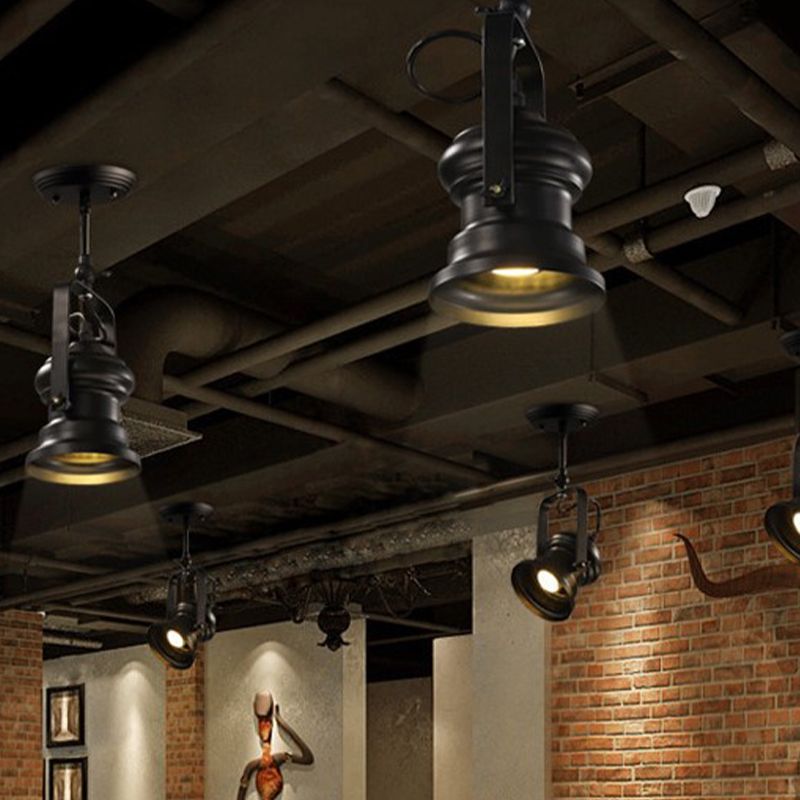 Several black Alessio bracketed heads beneath exposed dark beams and pipes, above brick walls, framed pictures and figure artwork.