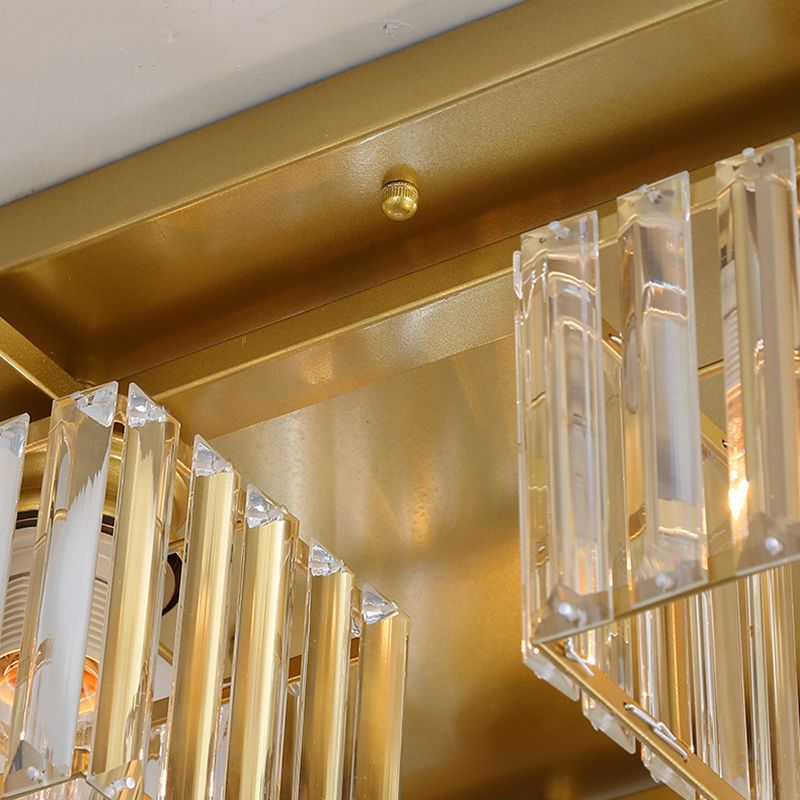Close-up of Kristy gold-toned rectangular canopy, straight bar, thumb nut, clear shade strips and a partly visible lit bulb.