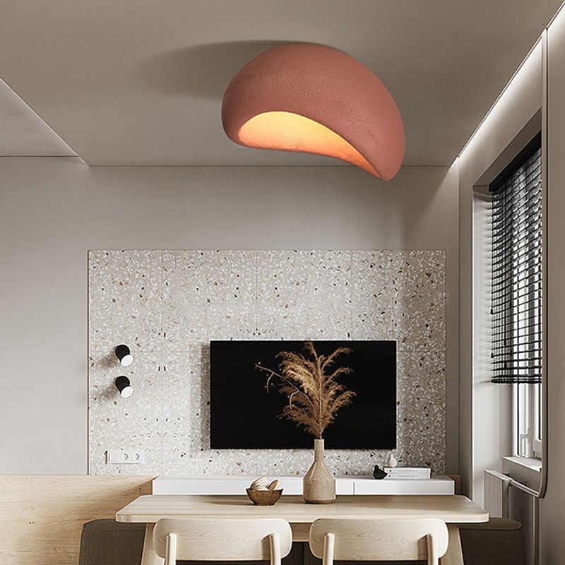 Red Byers light with a sloping opening over a dining table, near a patterned television wall, dried stems and dark blinds.