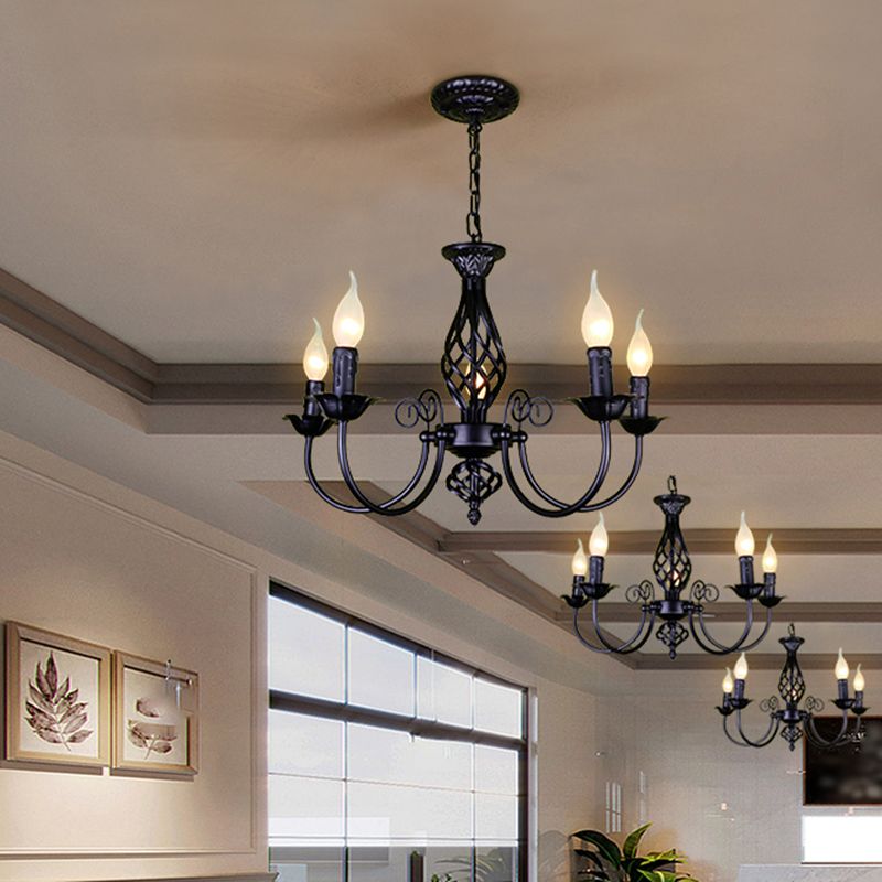Row of black Silva five-light chandeliers in pale interior with window and framed artwork, foreground showing four arms and central glow