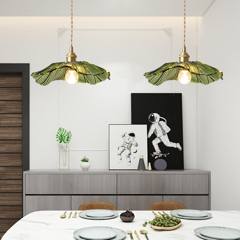Two green Carins pendants over a dining table with tableware, grapes, bread basket, grey sideboard, astronaut prints and plants.