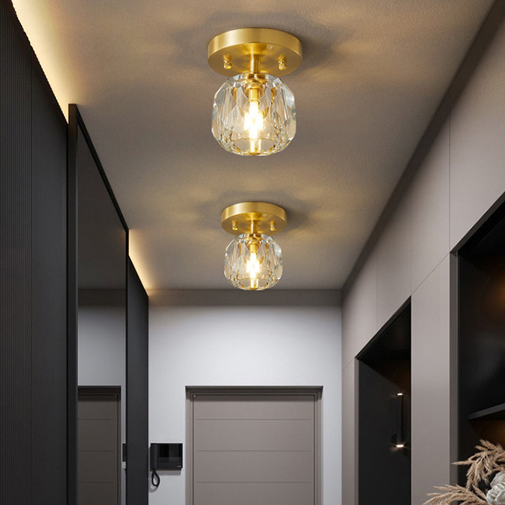 Two Kirsten fixtures in a dark grey hallway with intercom, grey door, black mirrored panel and dried branches.