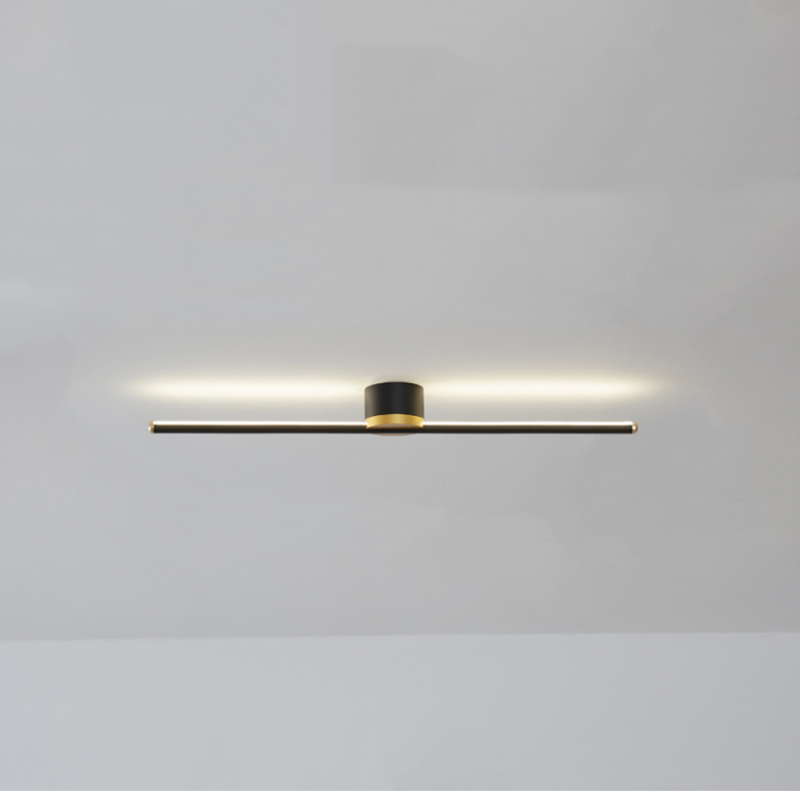 Black Edge horizontal bar with a bright halo on the ceiling above it, a black cylindrical mount and gold-tone rim and ends.