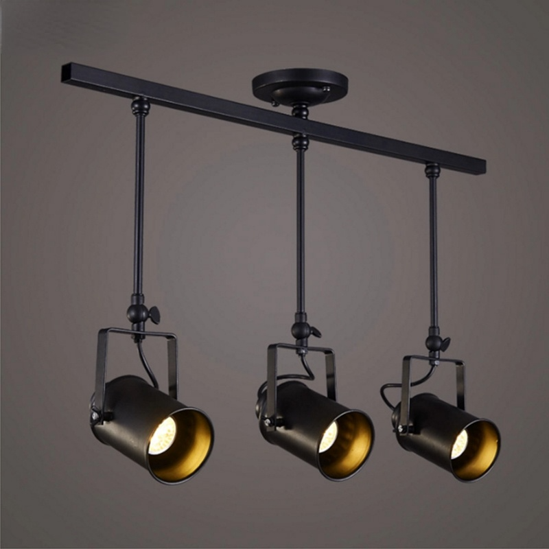 Alessio three-head black spotlight bar on grey backdrop, with rigid stems, square brackets, looped cables and lit centers.