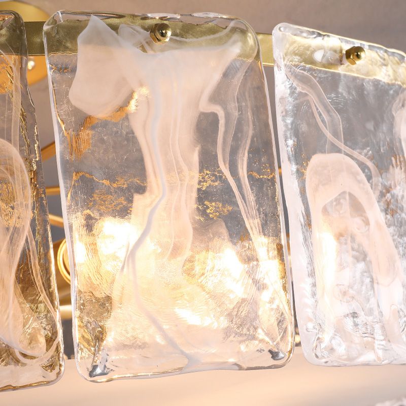Kirsten glass panels close-up showing wispy white patterns, gold-coloured flecks, top fixings and lit example bulbs behind.