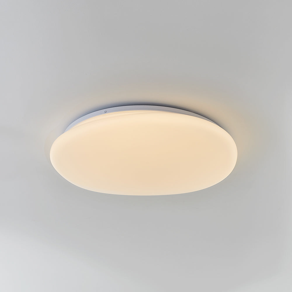 Oblique underside of Quinn pebble ceiling light showing a warm-looking luminous face and thin pale rim.