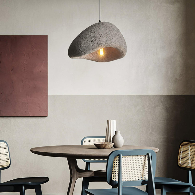 Gray textured cloud pendant above a wooden dining table with cane chairs, vases and red wall art