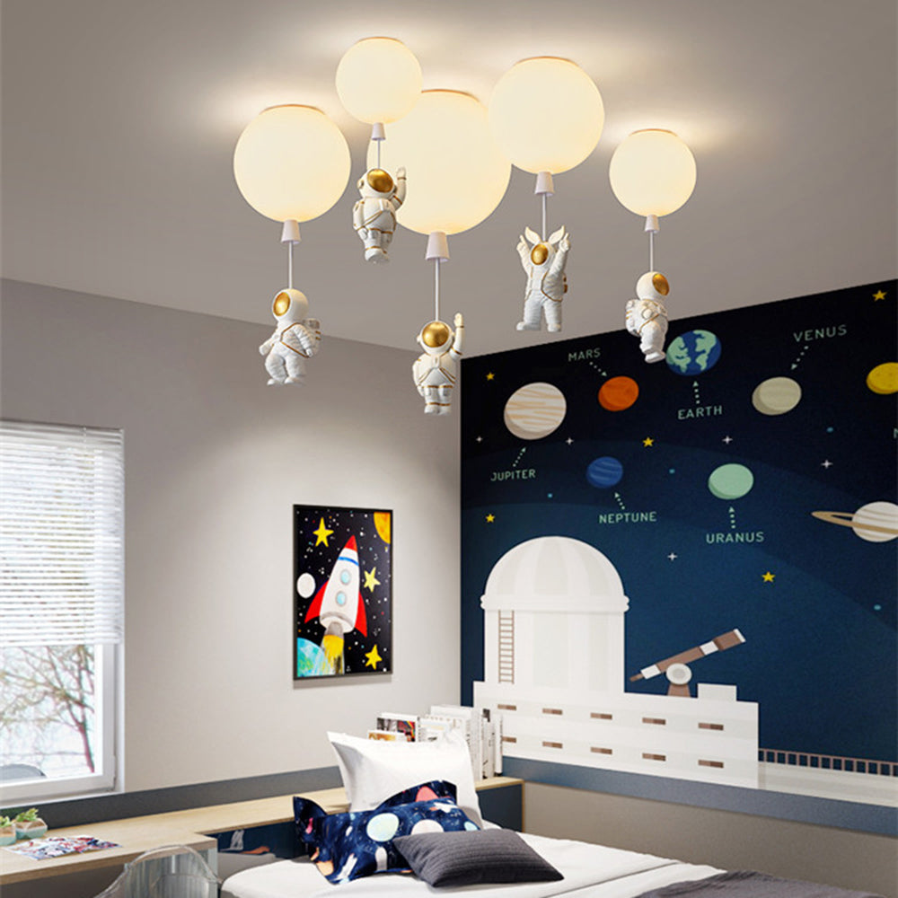Five pale glowing astronaut balloon fittings above a bed with space-print pillows, a planet mural, rocket picture, blinds and desk.