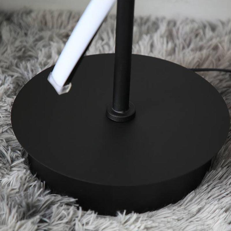 Close view of the black circular base, lower light-strip end and cable on a gray rug