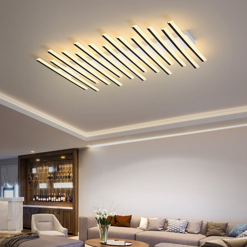 Lit Quinn linear ceiling light above a pale sofa and patterned cushions, with a vase, round table and wood display cabinet.
