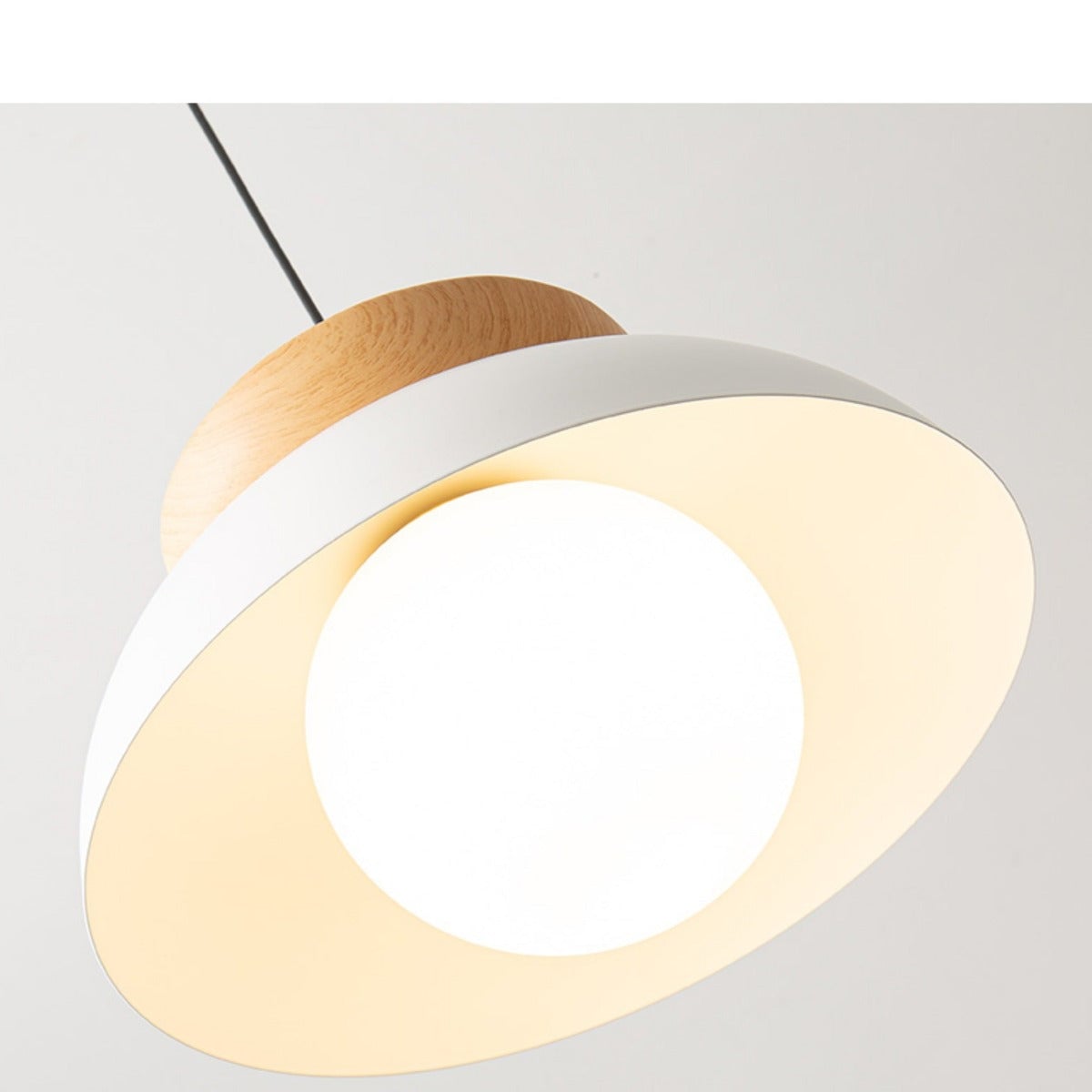 Angled underside of lit white dome pendant with a rounded white globe, pale illuminated interior and wood crown above