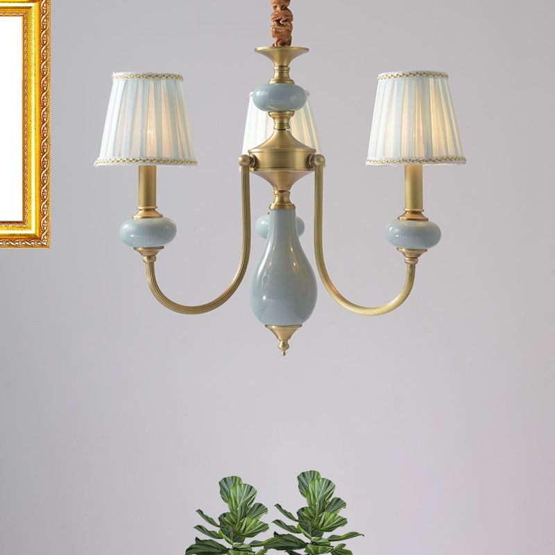 Three-light chandelier with blue decorative details and pale fabric shades