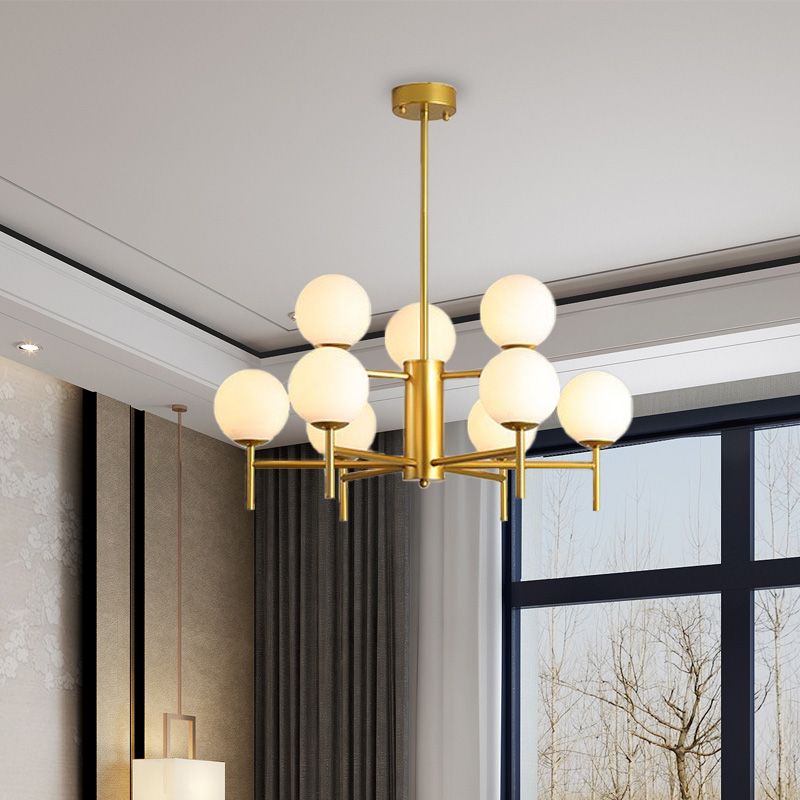 Gold nine-light Valentina chandelier beside tall windows