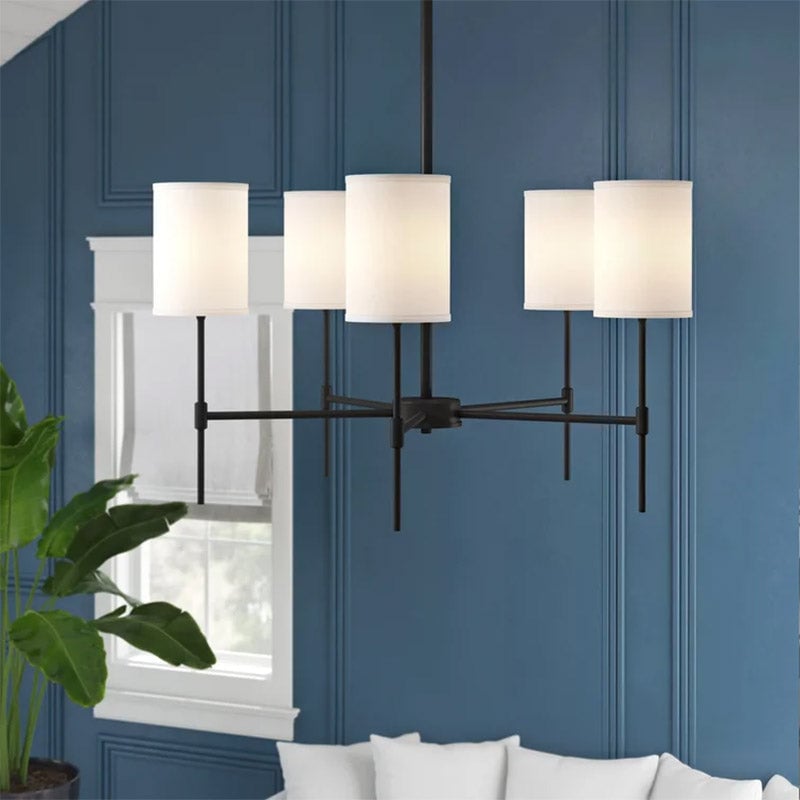 Illuminated black Silva chandelier against a blue paneled wall