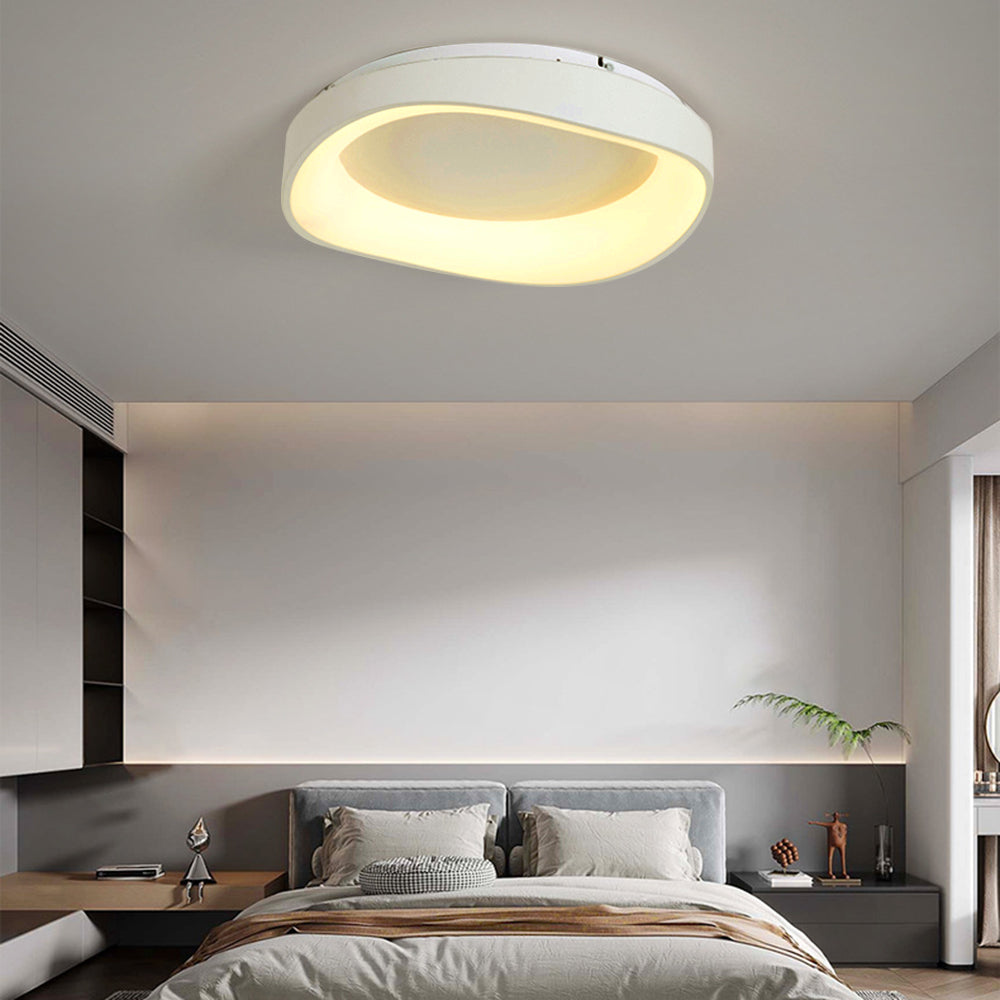 Single Arisha bowl above grey double headboard, cream pillows, brown-striped throw, plant and curved cove-light wall.