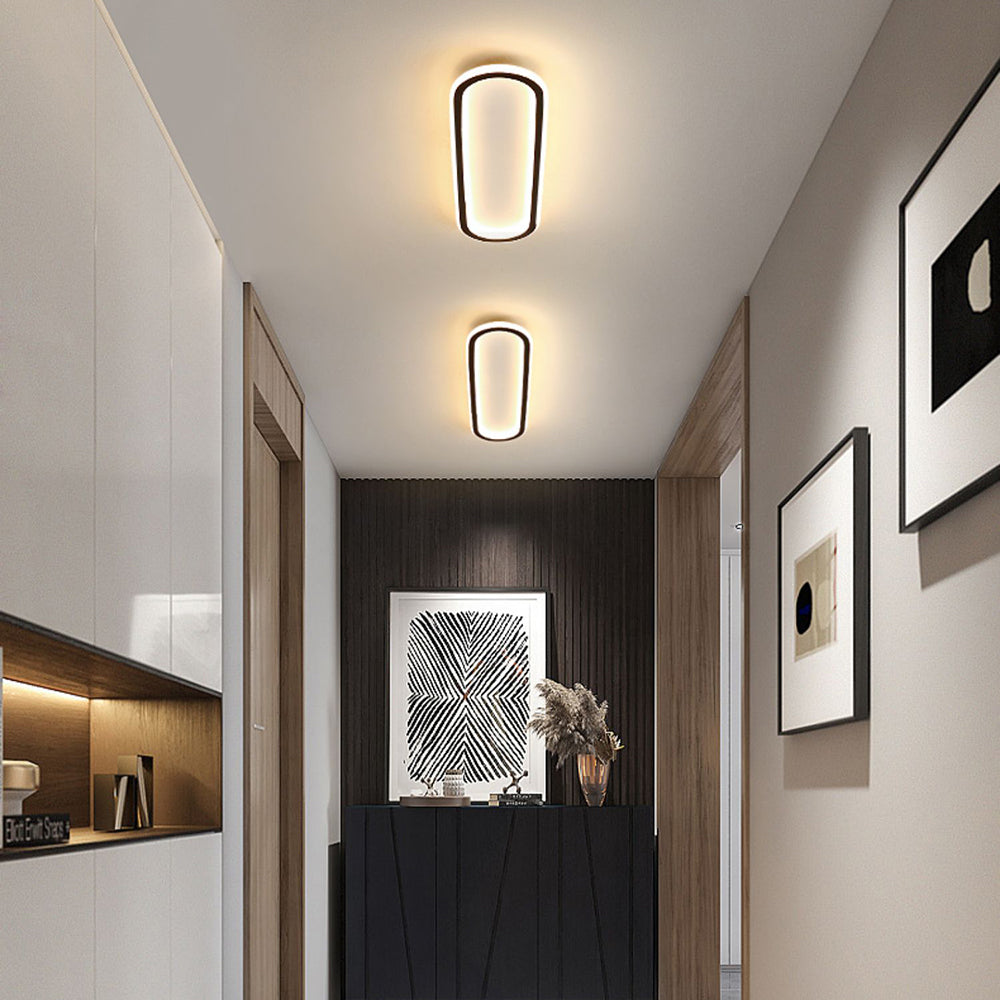Two Black Quinn lights in a hallway with pale cabinets, wood shelf, slat wall, geometric artwork and dried flowers.