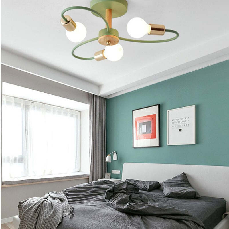 Close view of green three-head ceiling light with gold-tone holders and wood-grain centre above a bed