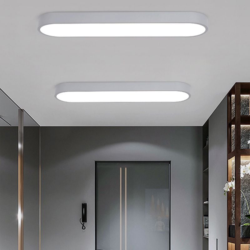 Two white Quinn ceiling fixtures above an entrance door and intercom, beside a mirror and dark wood divider with white flowers.