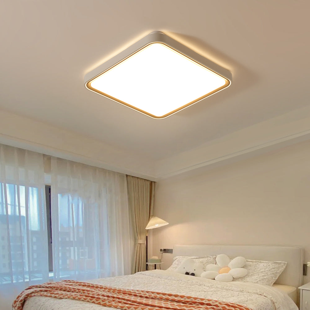Square Quinn above a pale bed with a white flower cushion, stuffed bear, orange patterned throw and separate bedside lamp.