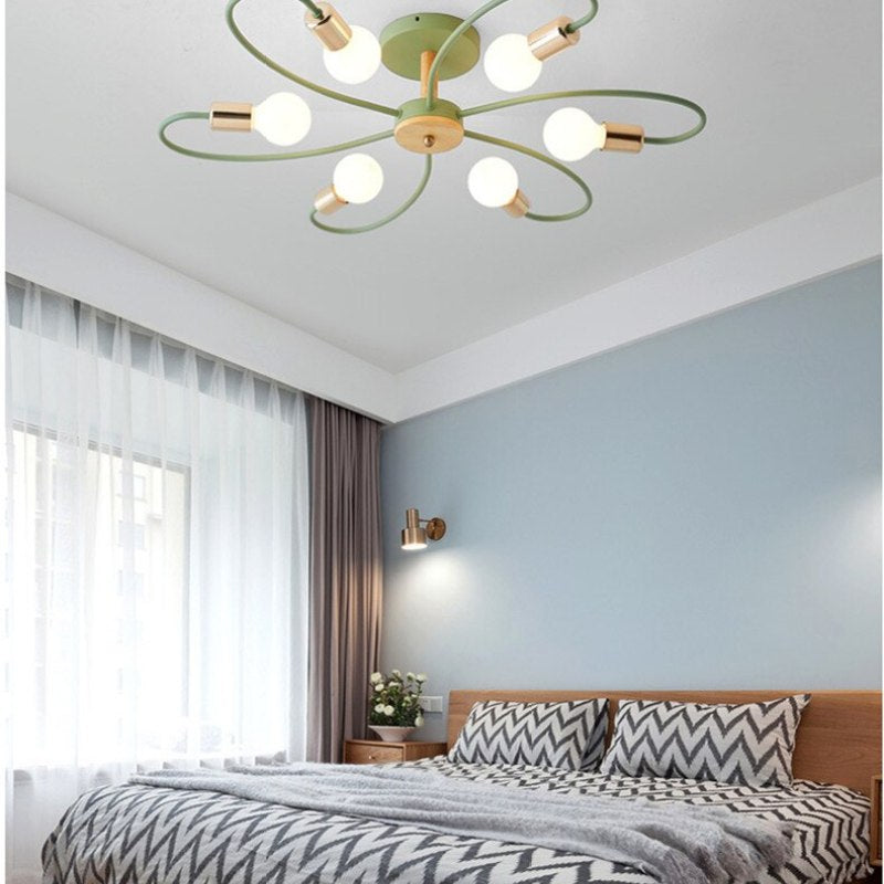 Green six-head flower ceiling light glowing above a wooden bed with patterned bedding beside a window